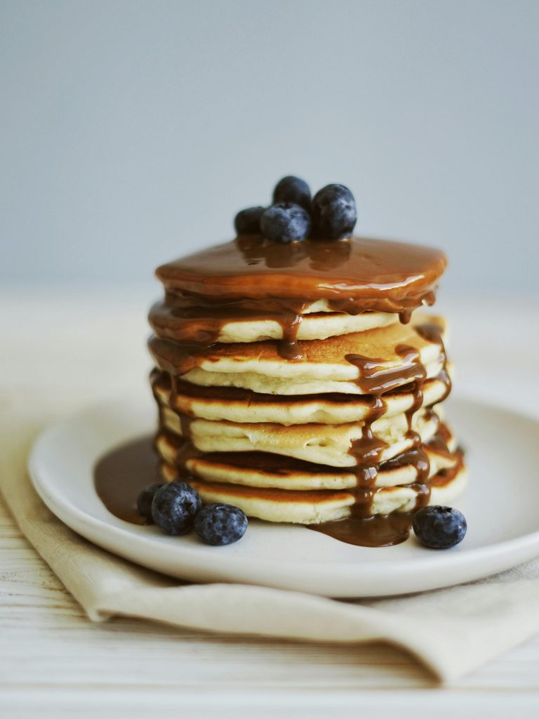 pexels-photo-3323680-3323680 Mouth-watering pancakes stacked with blueberries and syrup on a plate.