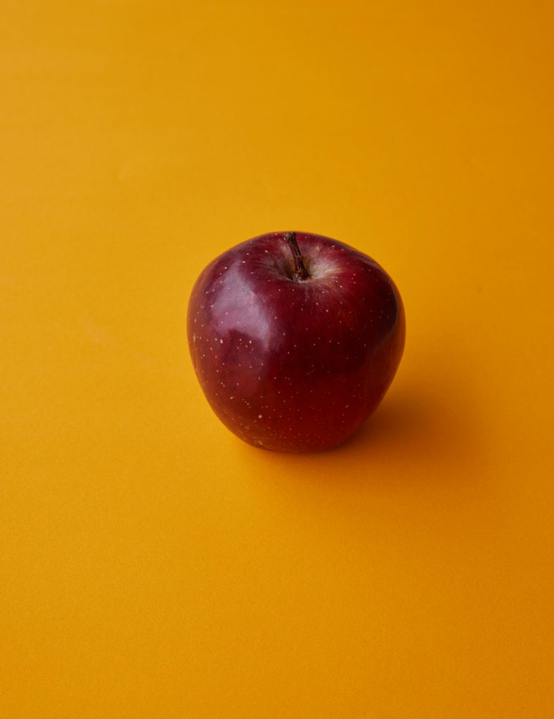 pexels-photo-6157055-6157055 Close-up of a ripe red apple on a vibrant yellow background, perfect for food and nutrition content.